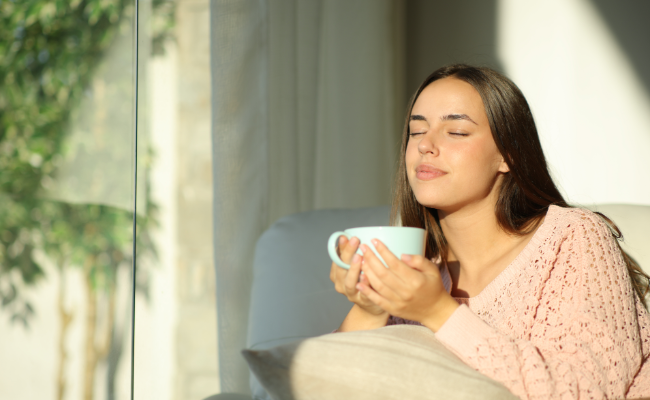 Woman enjoying a calming herbal tea ritual in a bright space, representing HR Wellness relaxation and mindful wellbeing